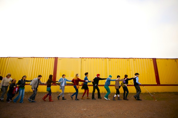 Artist Carmen Papalia takes participants on a non-visual walking tour. They form a single-file line with one hand to the shoulder of the person in front of them--Papalia leads with a white cane.